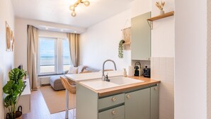 A modern kitchen with a central island, a sink, and a built-in oven. - Tastefully furnished apartment with sea view (Koksijde)