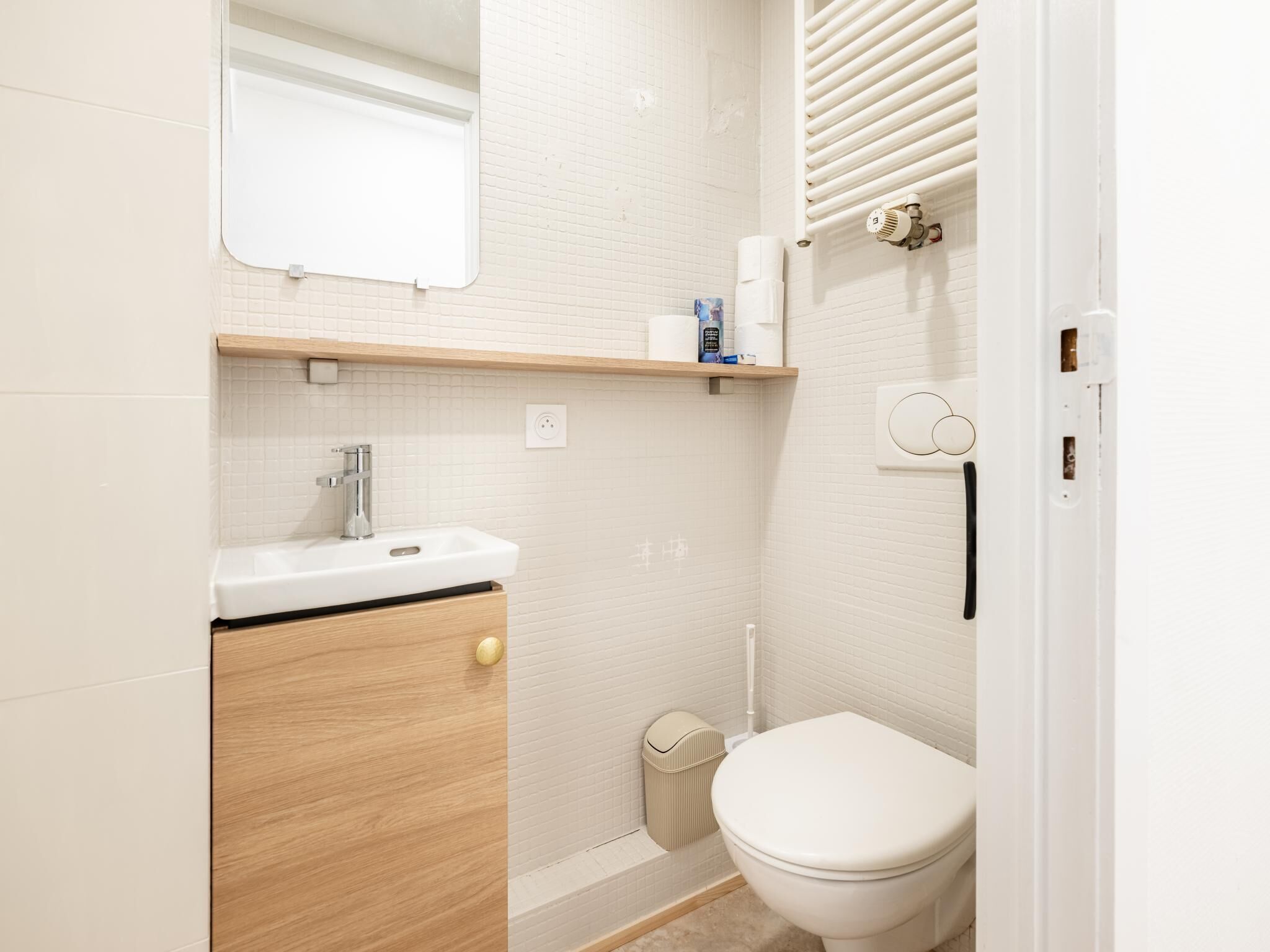 Een badkamer met een wit wastafelmeubel, toilet en een handdoekhouder.