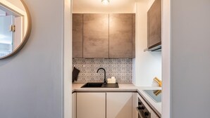 A compact kitchen with a sink, faucet, and oven. - Cozy apartment & terrace, 100 m from sea (Koksijde)