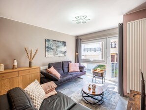 A modern living room with a sofa, coffee table, and artwork on the wall. - Cozy apartment & terrace, 100 m from sea (Koksijde)