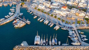 An aerial view of a marina with boats docked, surrounded by white buildings with red roofs. - Paros Studio 8th Central Naousa (Naousa)