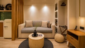 A modern living room with a sofa, a coffee table, a wooden cabinet, and a hanging light fixture. - Paros Studio 8th Central Naousa (Naousa)