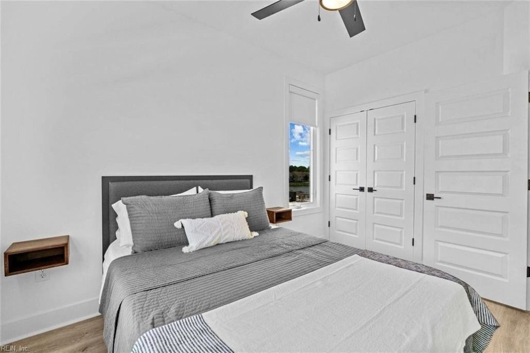 A bedroom with a bed, a ceiling fan, a wardrobe, and a nightstand.