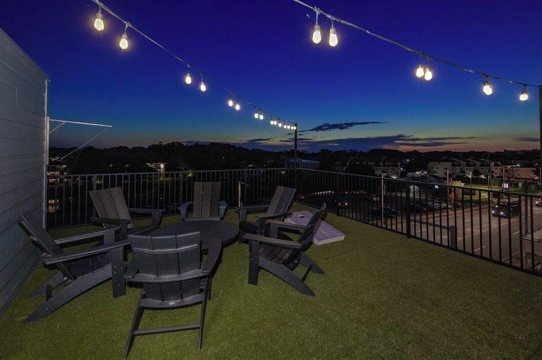 Eine Außenpatio mit Stühlen, einem Tisch, Lichterketten und Blick auf die Stadtlandschaft.