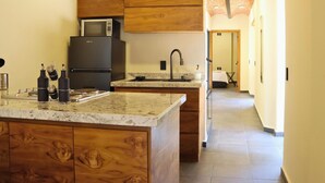 Una cucina con mobili in legno, un frigorifero nero, un forno a microonde e un piano di lavoro in granito.