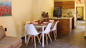 Una cucina moderna con isola centrale, sedie bianche e tavolo da pranzo per quattro persone.