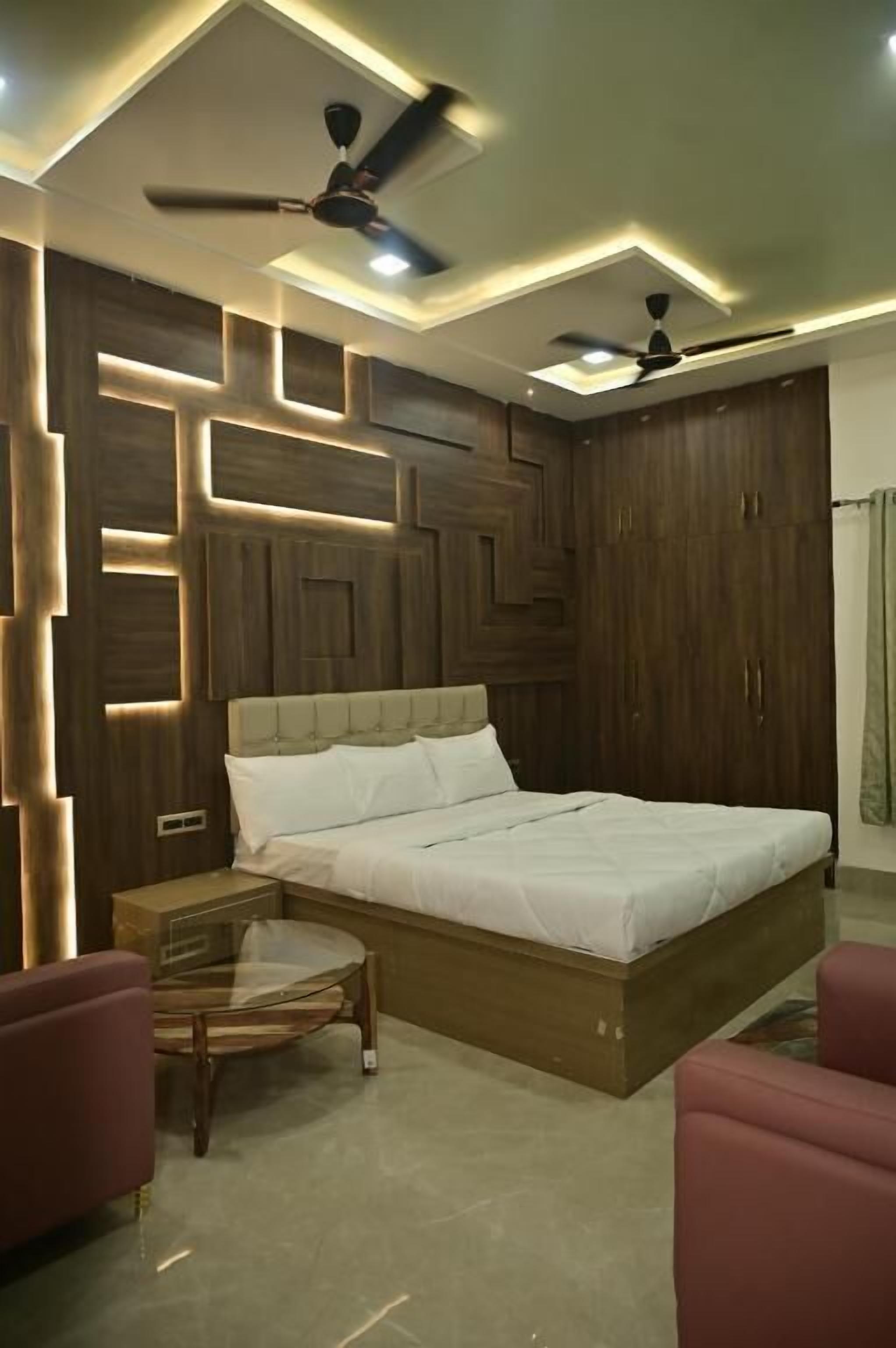 A bedroom with a bed, two nightstands, a glass table, and two chairs.