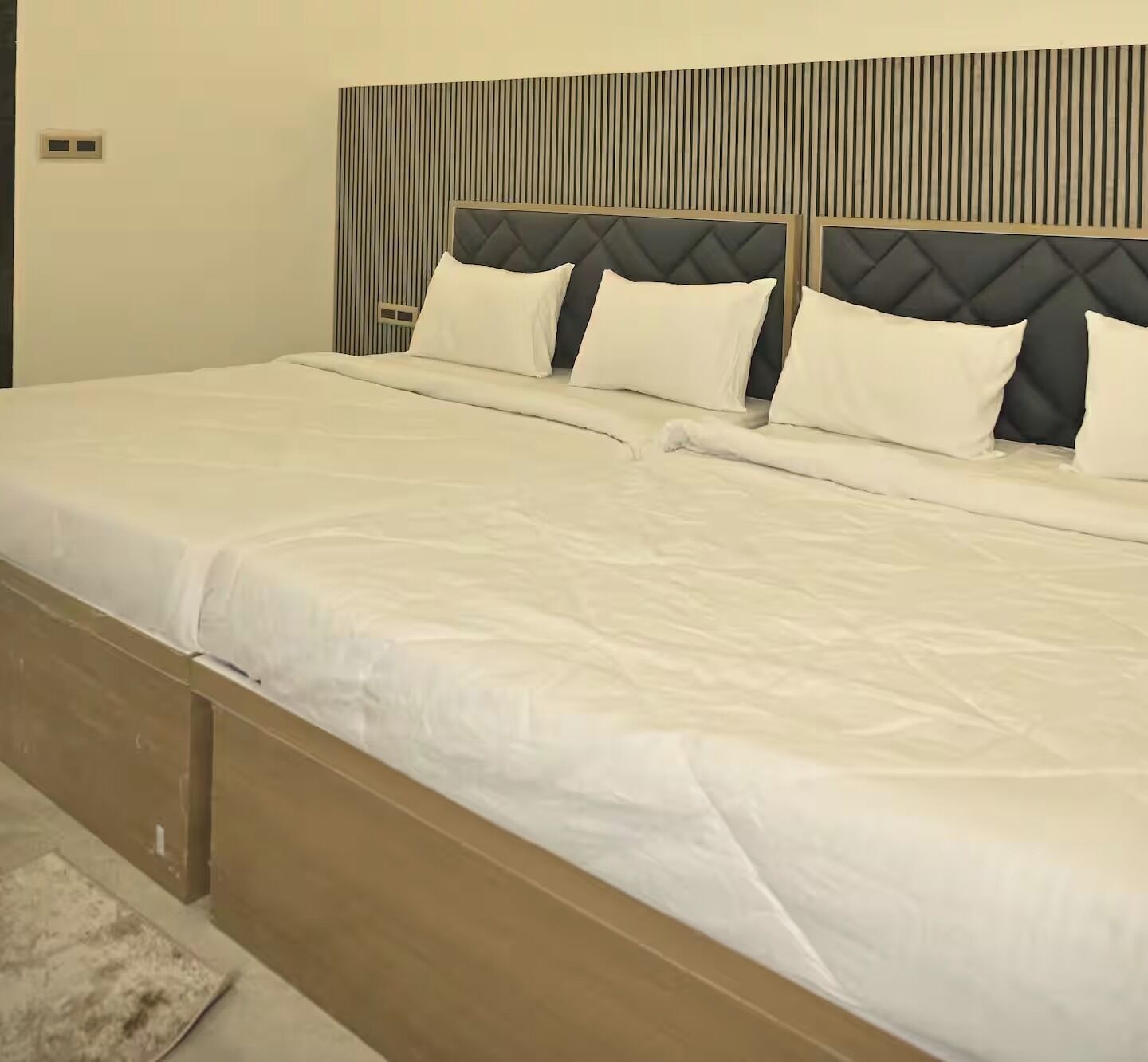 A double bed with a quilted headboard, two pillows, and a wooden bedside table.