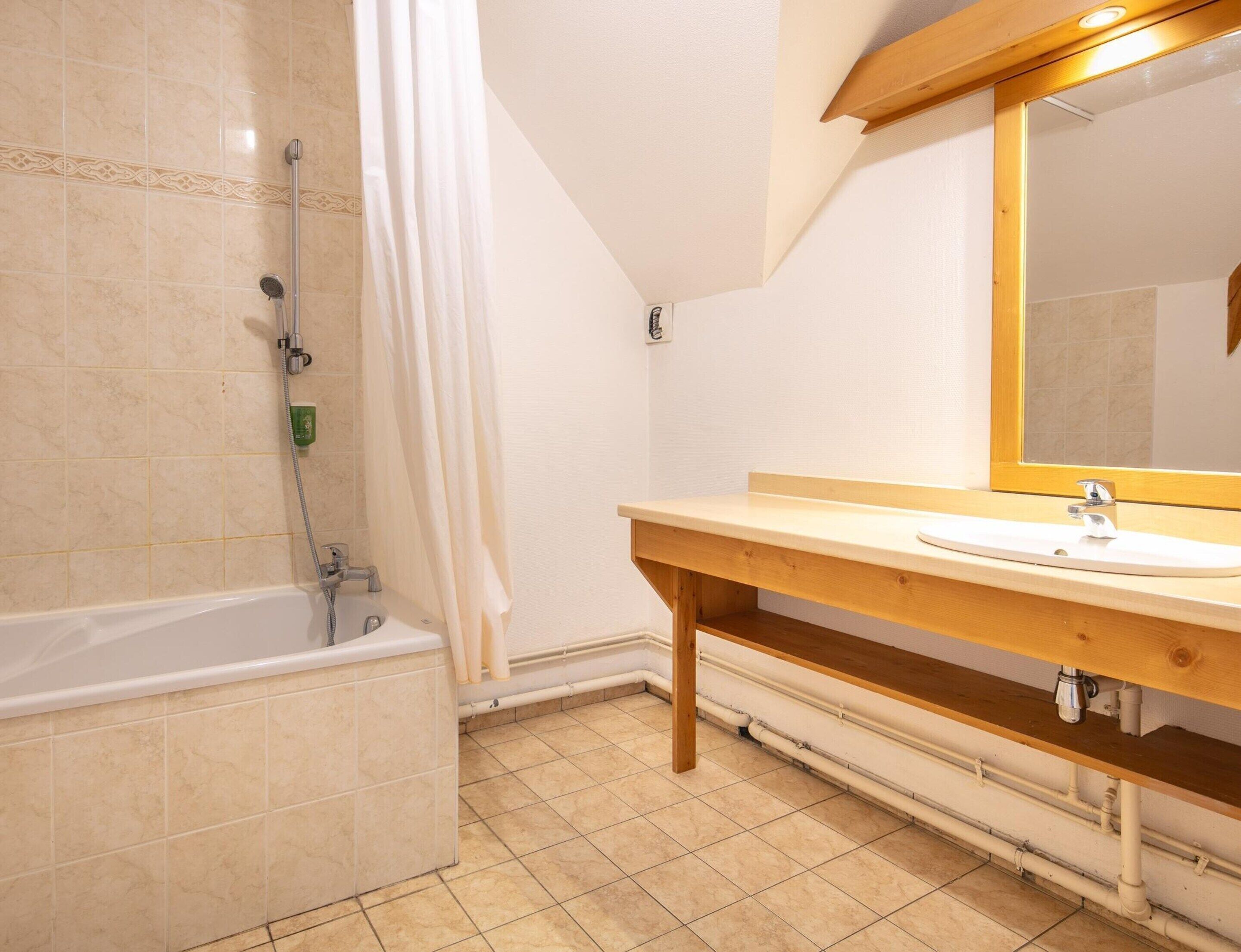 A bathroom with a bathtub, a sink, a mirror, and a showerhead.