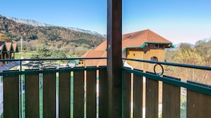 A wooden building with a sloped roof, a wooden fence, and a mountainous landscape in the background. - Duplex for 12 Near Lake Annecy (Giez)