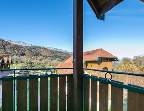 A wooden building with a sloped roof, a wooden fence, and a mountainous landscape in the background. - Duplex for 12 Near Lake Annecy (Giez)