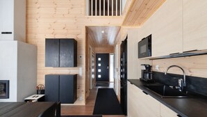 A modern kitchen with wooden cabinetry, a black countertop, and a built-in stove. - Porevillas Iso-Syöte B | Jacuzzi & Sauna (Syöte)