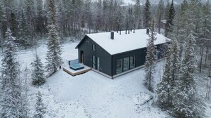 A modern house with a snow-covered roof, surrounded by a forest. - Porevillas Iso-Syöte B | Jacuzzi & Sauna (Syöte)