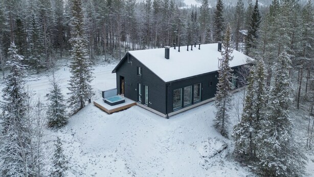 A modern house with a dark exterior, large windows, and a covered outdoor area. - Porevillas Iso-Syöte B (Syöte)