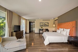 Ein Hotelzimmer mit einem großen Bett, einem Schreibtisch, einem Fernseher und Blick ins Freie.