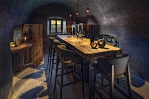 Un'area pranzo rustica con un tavolo in legno, sgabelli da bar e lampade a sospensione.