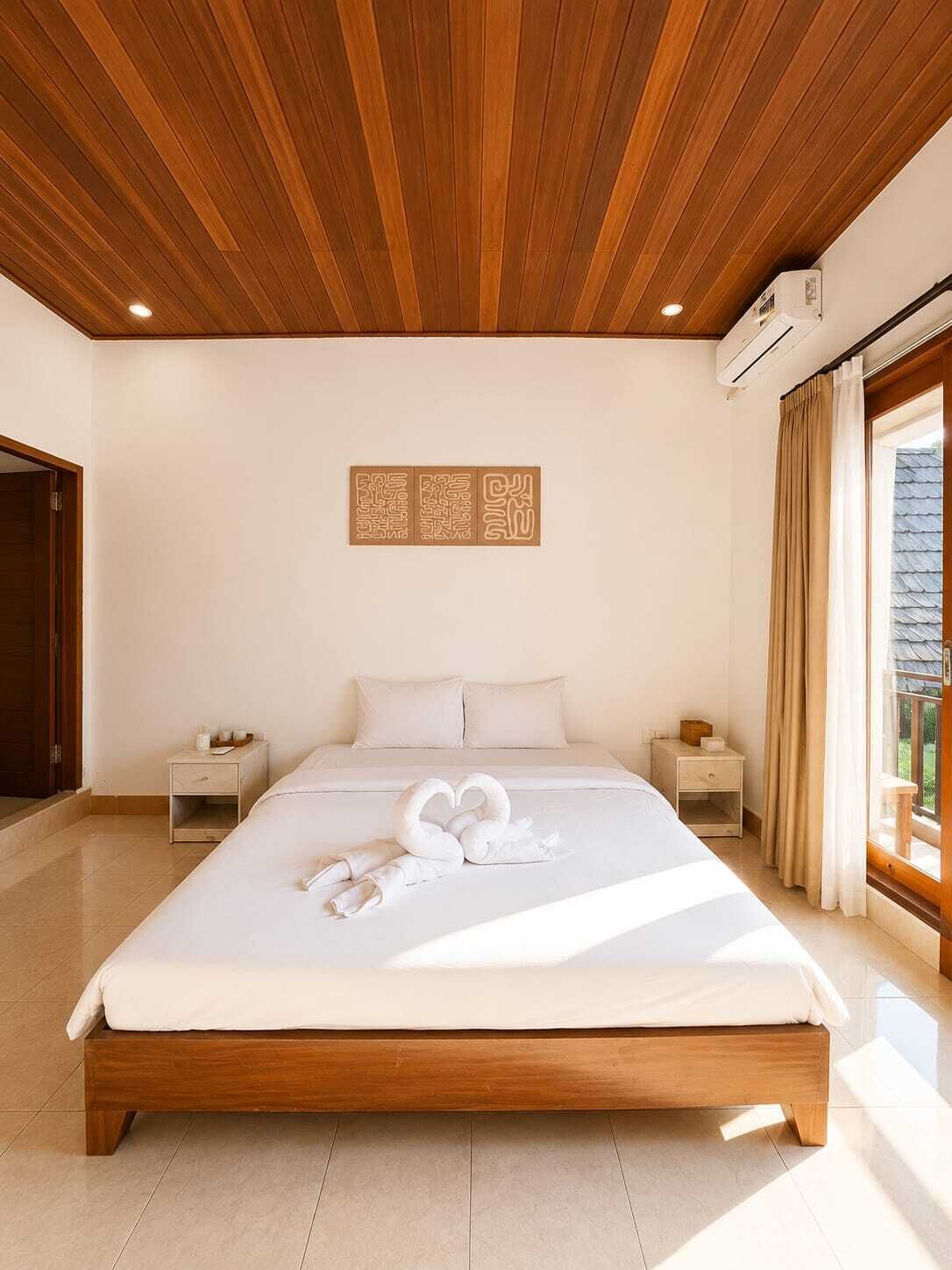 Habitación de hotel con techo de madera, cama con ropa blanca, aire acondicionado montado en la pared y ventana con cortinas.