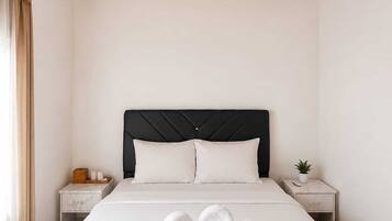 Habitación de hotel con techo de madera, una cama con ropa blanca, dos mesitas de noche y un buró con una planta.