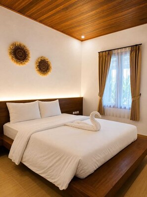 A hotel room with a wooden ceiling, a bed with white bedding, two wall-mounted decorative items, and a window with curtains.