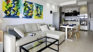 A modern living room with a sofa, coffee table, and abstract art on the wall. - Sunstay Benalbeach Juana Flat I Benalmadena (Benalmádena)
