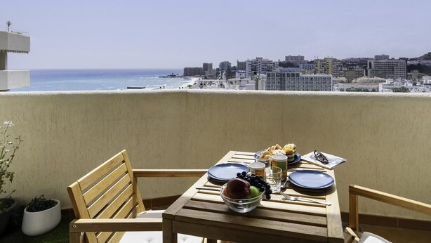 A balcony with a table set for two, overlooking a cityscape and the sea. - Sunstay Benalbeach Juana Flat I Benalmadena (Benalmádena)