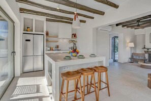Eine moderne Küche mit einer zentralen Kochinsel, Holzbarhocker und einer hängenden Pendelleuchte.
