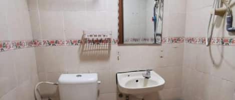 Un baño pequeño con inodoro, lavamanos y ducha.