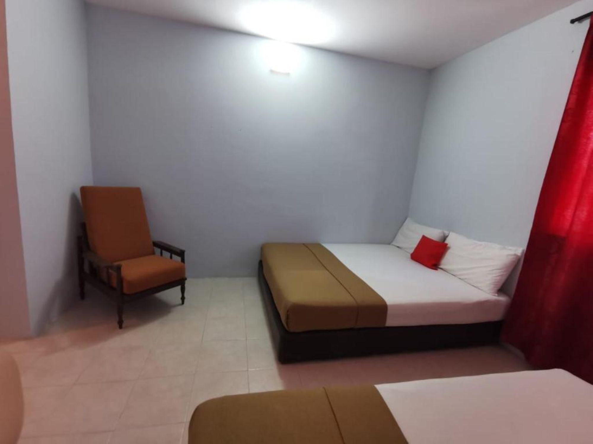 Una habitación de hotel pequeña y con una cama, una silla y una mesita de noche.