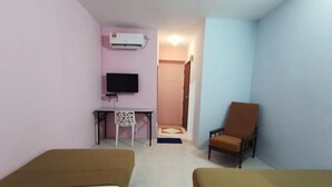 Habitación de hotel con dos camas, un escritorio con silla, televisión y aire acondicionado.