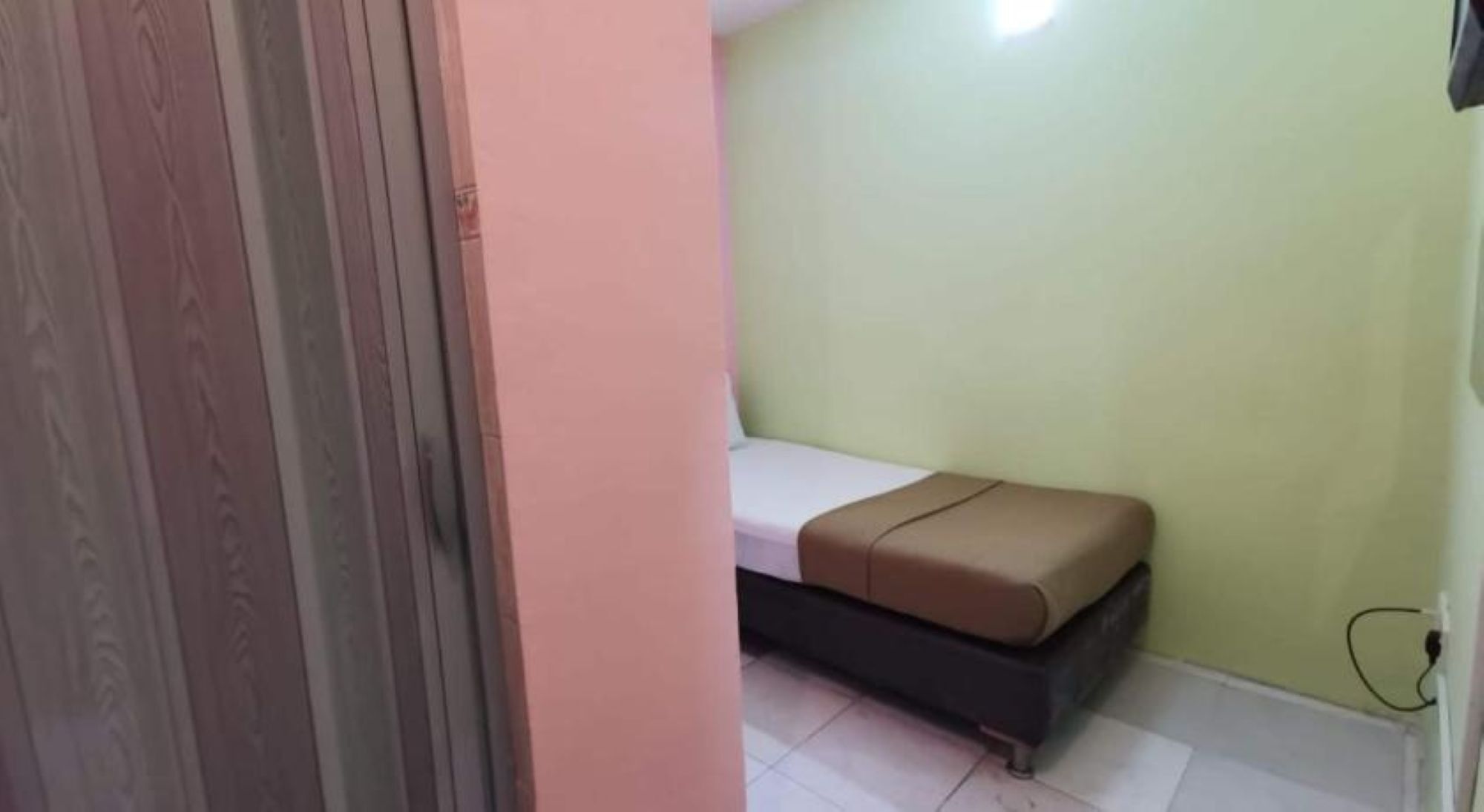 A room with a bed, a pink wall, and a green wall.