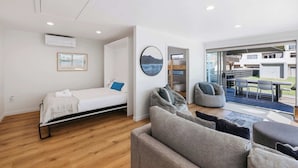 Ein modernes Zimmer mit Bett, einer Couch, Sitzsäcken, einer runden Wanddekoration und Blick auf eine Terrasse.