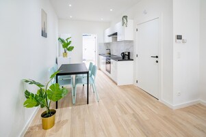 Cozinha moderna com armários brancos, bancada preta e um vaso com planta.