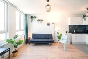 Uma sala de estar moderna com sofá, mesa de jantar, cozinha e uma janela grande.