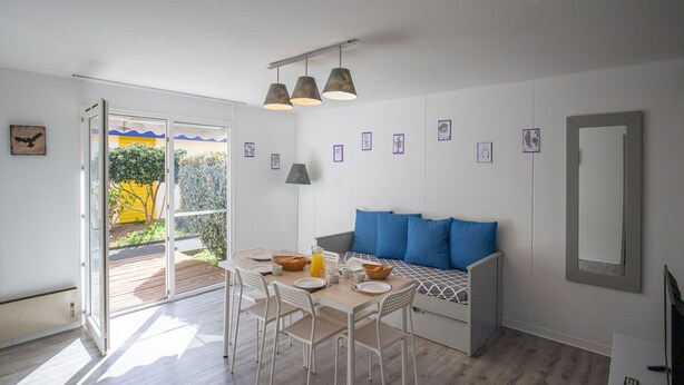 Un interior moderno con una zona de comedor, un sofá con cojines azules y un espejo grande.