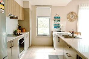 A modern kitchen with a built-in oven, a sink, and a window. - 3BR Beachfront Penthouse in Huskisson – Jervis Bay (Huskisson)