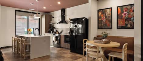 A modern kitchen with a central island, stainless steel appliances, and a dining area with a round table and chairs.