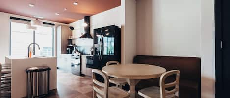 Une cuisine moderne avec un coin repas, comprenant une table ronde et des chaises, un réfrigérateur et une poubelle.