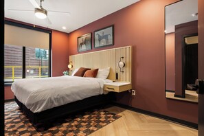 Un dormitorio moderno con cama, mesita de noche, lámpara de pared y una obra de arte.