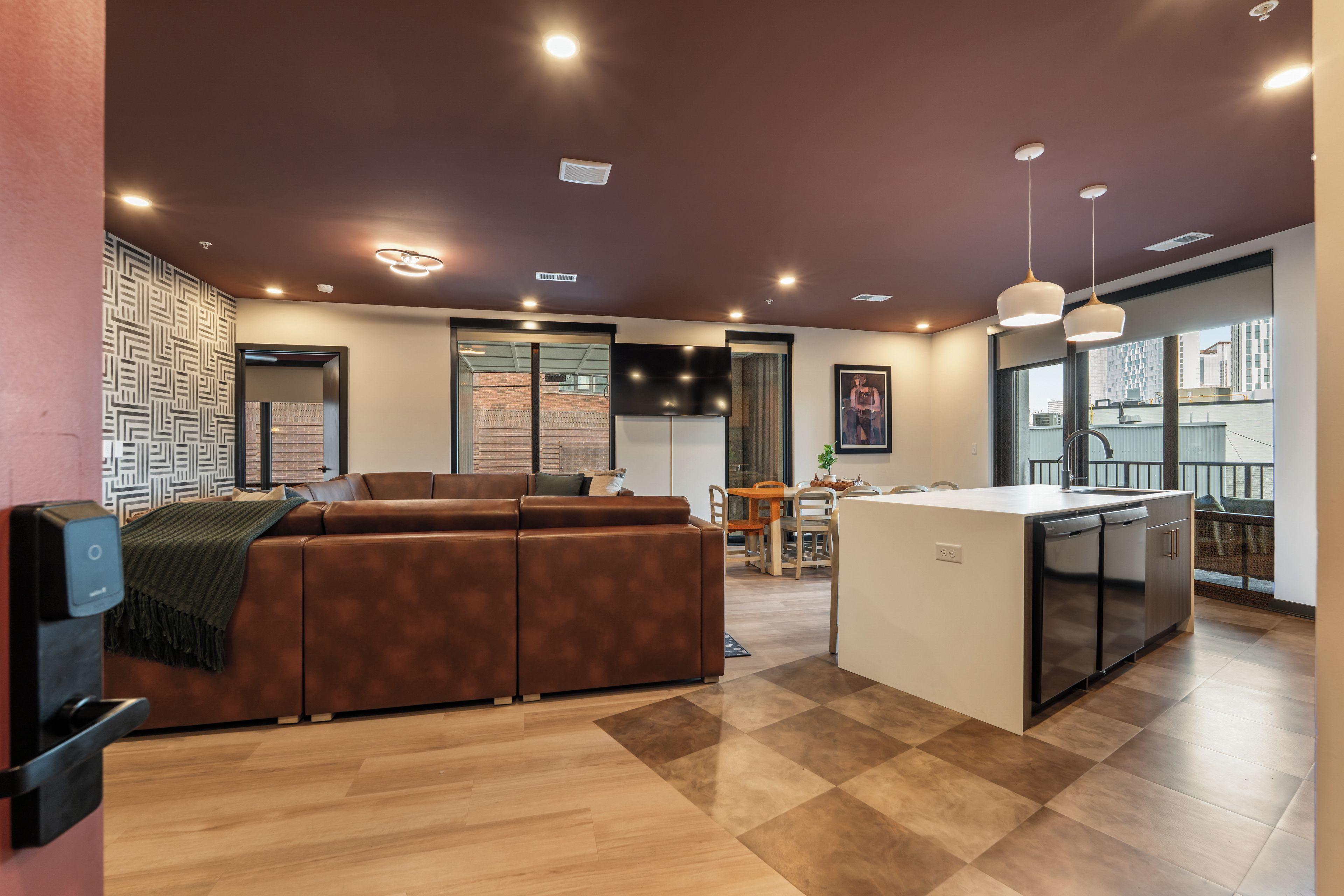 A modern kitchen with a central island, a dining area with a table and chairs, and a seating area with a sofa.