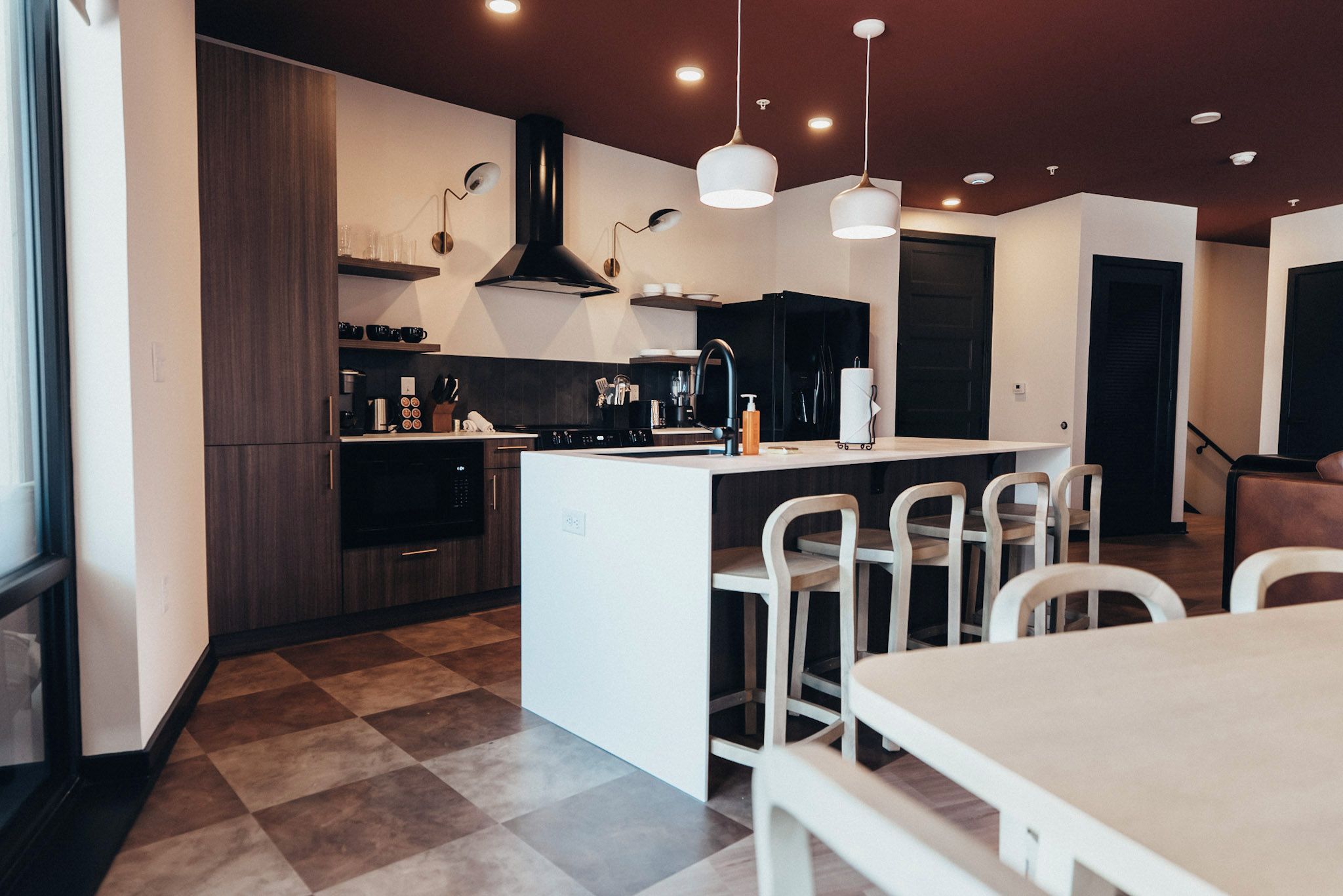 A modern kitchen with a central island, dark cabinetry, and a checkered floor.
