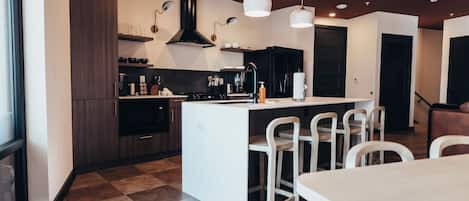 Una cocina moderna con una isla central, armarios oscuros y piso a cuadros.