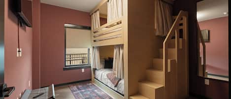 Una habitación con literas, un escritorio, una silla, una alfombra y una escalera.