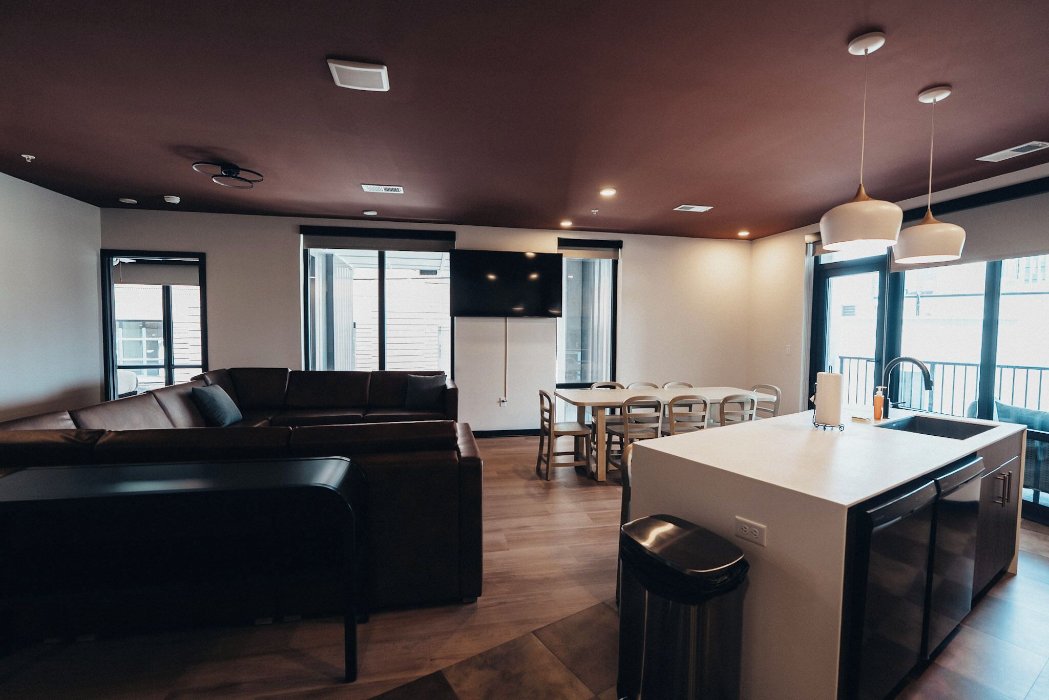 Una cocina moderna con una isla central, un comedor con mesa y sillas, y una sala de estar con sofá y televisor.