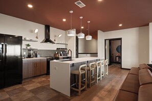 A modern kitchen with a central island, bar stools, and a built-in oven. - Superior Suite - Unit 203 (Nashville)