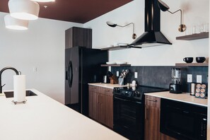 Een moderne keuken met een centraal kookeiland, een fornuis, een vaatwasser en een koffiezetapparaat.