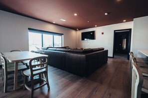 A modern living room with a sofa, a dining table with chairs, and a TV mounted on the wall. - Superior Suite - Unit 203 (Nashville)