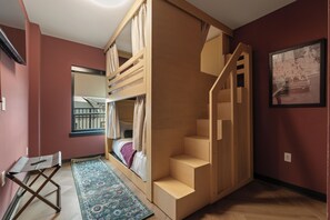 A room with a bunk bed, a small desk, a chair, a patterned rug, and a staircase. - Superior Suite - Unit 203 (Nashville)