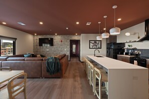 A modern kitchen with a central island, bar stools, and a dining area with a table and chairs. - Superior Suite - Unit 203 (Nashville)