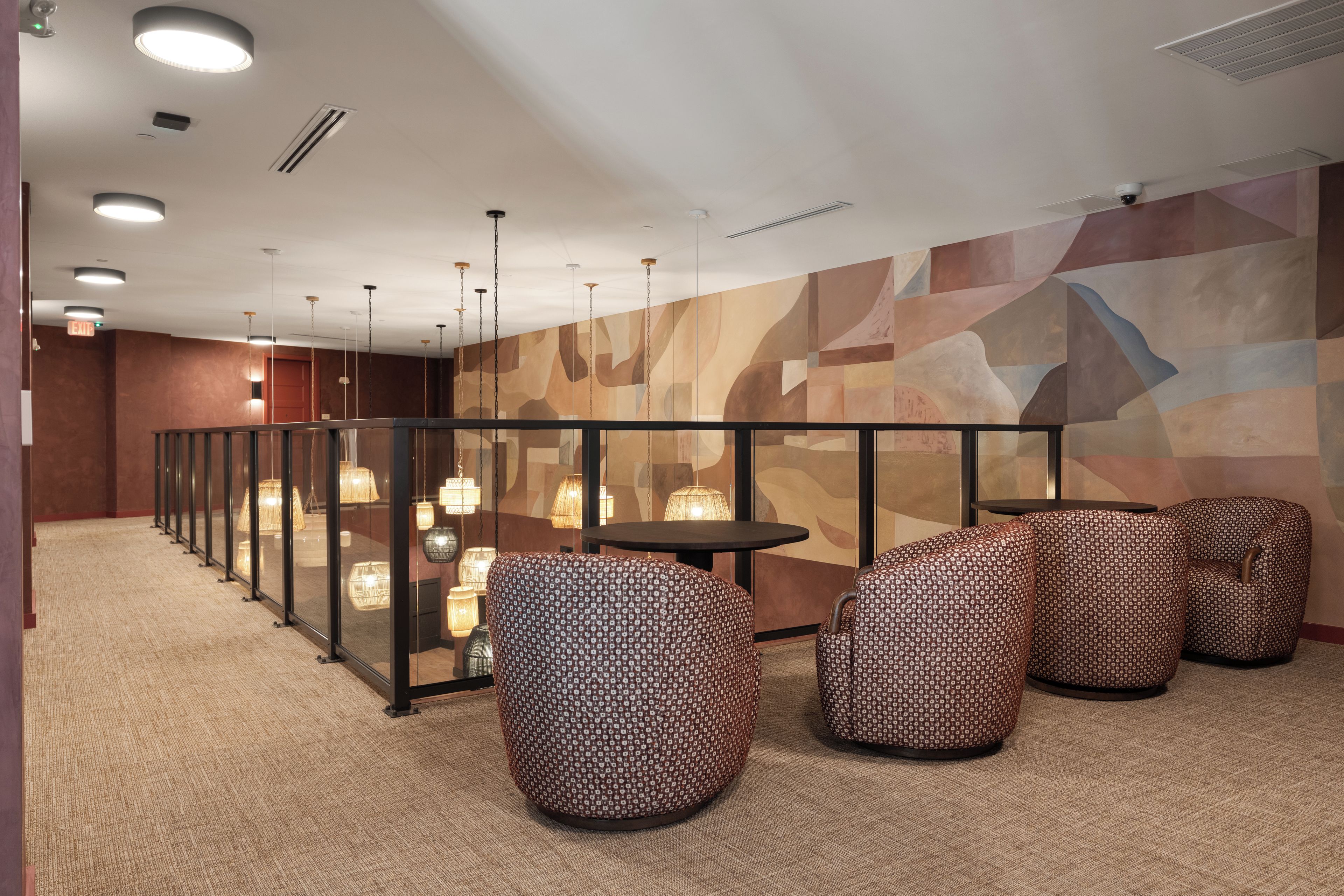 A modern interior with a long corridor, glass partitions, and patterned seating.