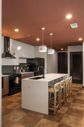 A modern kitchen with a central island, bar stools, a stainless steel range, and pendant lighting. - Superior Suite - Unit 204 (Nashville)